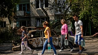Славянск. Жители города несут воду в укрытия мимо здания, пострадавшего от ракетного удара