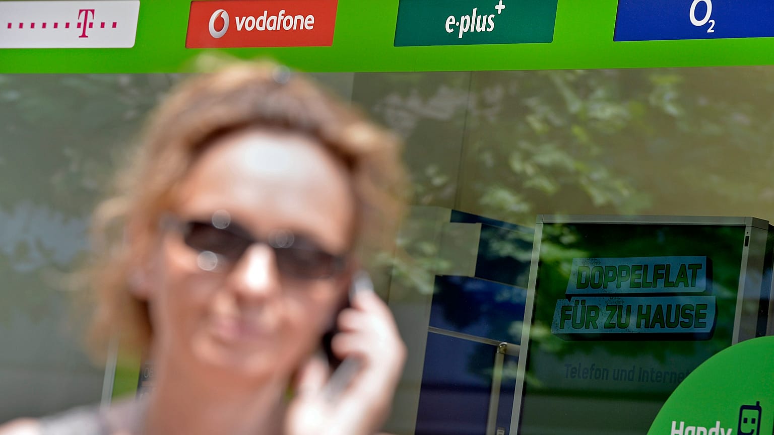 Una mujer sostiene un teléfono mientras pasa por una tienda de teléfonos móviles en Gelsenkirchen, Alemania, el martes 23 de julio de 2013.
