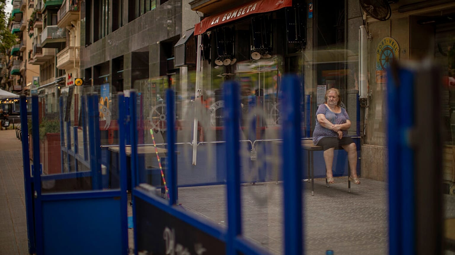 Eine Frau sitzt auf einem Tisch vor einer geschlossenen Bar während der Pandemie in Barcelona, 01.06.2020