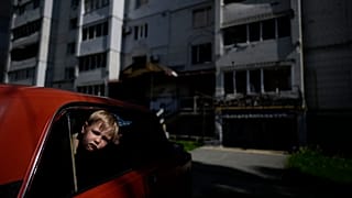 Kinder in einem Auto vor einem durch Angriffe zerstörten Gebäude in Borodjanka, am Stadtrand von Kiew (31. Mai 2022)
