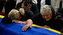 The mother, right, and sister of Army Col. Oleksander Makhachek mourn over the coffin with his remains during a funeral service in Zhytomyr, Ukraine, Friday, June 3, 2022.