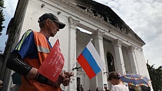 Un hombre con una bandera rusa en el centro de Mariúpol