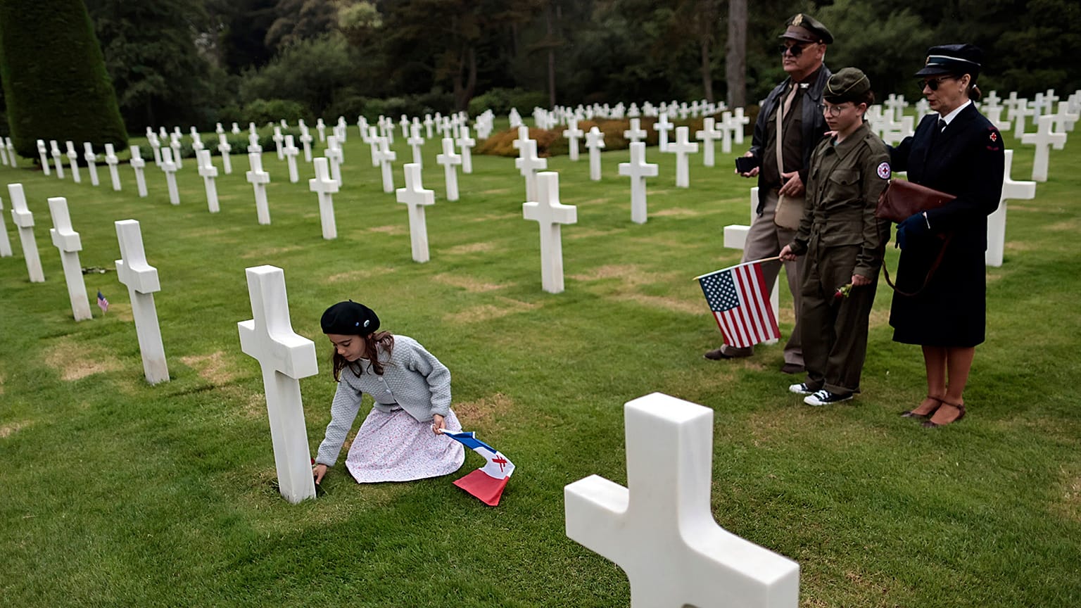 Alice, let, puts a flower, as family members Remy, Dalma and Sylvie look on in the 1944 headstones of the US cemetery of Colleville-sur-Mer, Normandy on 4 June 2022