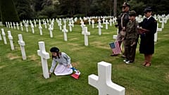 Alice, let, puts a flower, as family members Remy, Dalma and Sylvie look on in the 1944 headstones of the US cemetery of Colleville-sur-Mer, Normandy on 4 June 2022