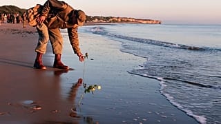 World War II reenactor put roses and flowers at dawn on Omaha Beach, in Saint-Laurent-sur-Mer, Normandy