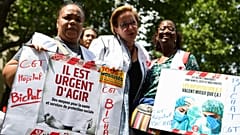 Protestors hold signs reading "It's urgent to act" in support of French hospital staff in Paris