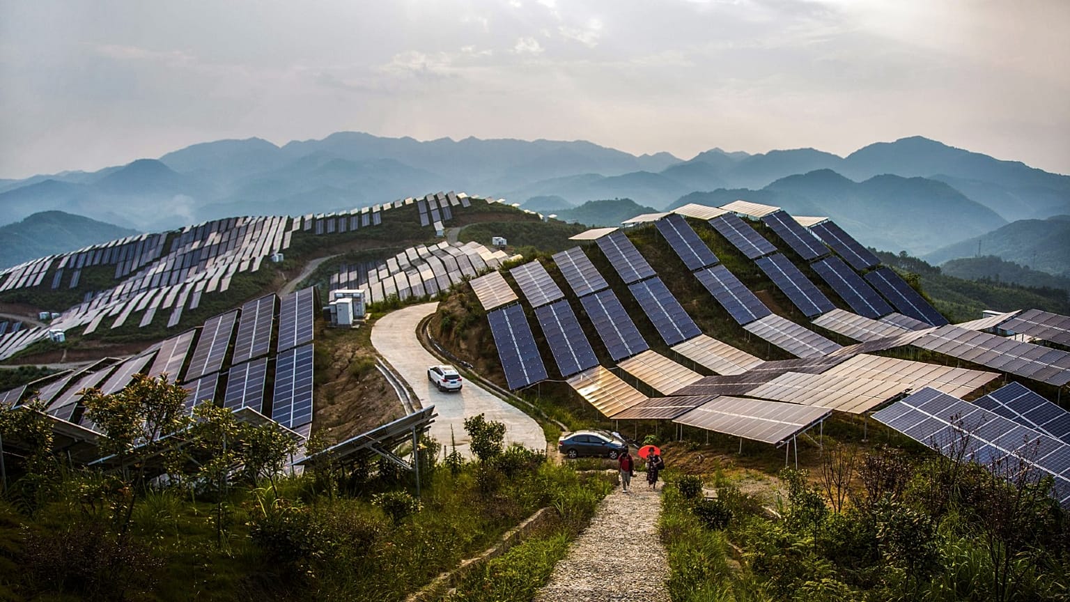 People walk past solar panels at a photovoltaic power station in Songxi county in southeastern China's Fujian province. 