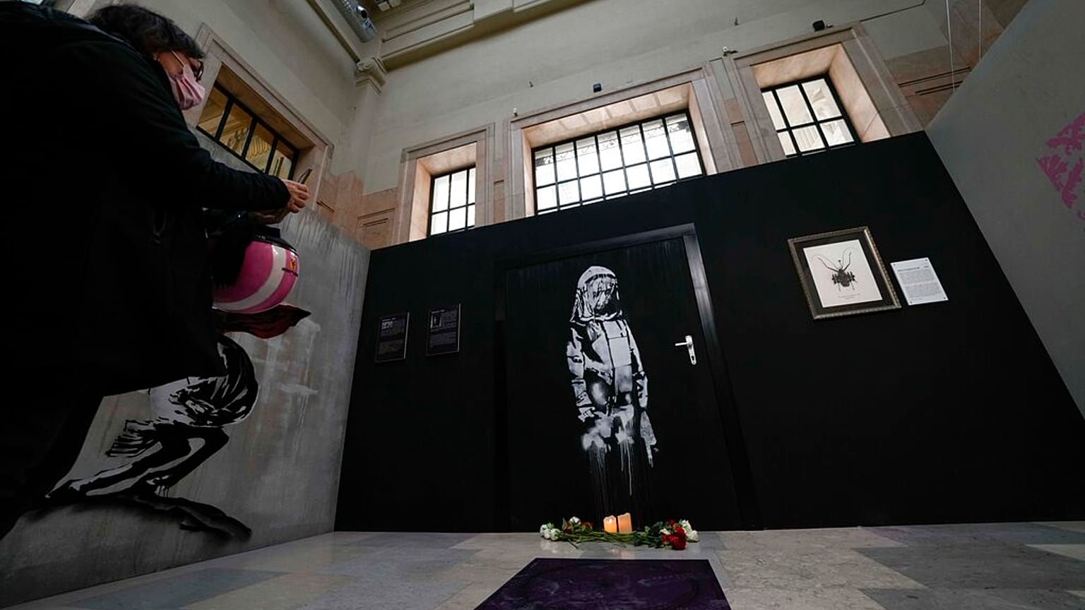 A visitor takes pictures of "Bataclan", a reproduction of a mural by British artist Banksy