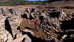 A man walks among the ruins of the previously-submerged village of Vilar. It has risen above the waters of the Zezere River due to drought. Feb. 17, 2022.
