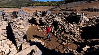 A man walks among the ruins of the previously-submerged village of Vilar. It has risen above the waters of the Zezere River due to drought. Feb. 17, 2022.