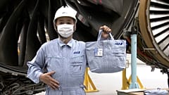An ANA worker models a bag made from his recycled workwear