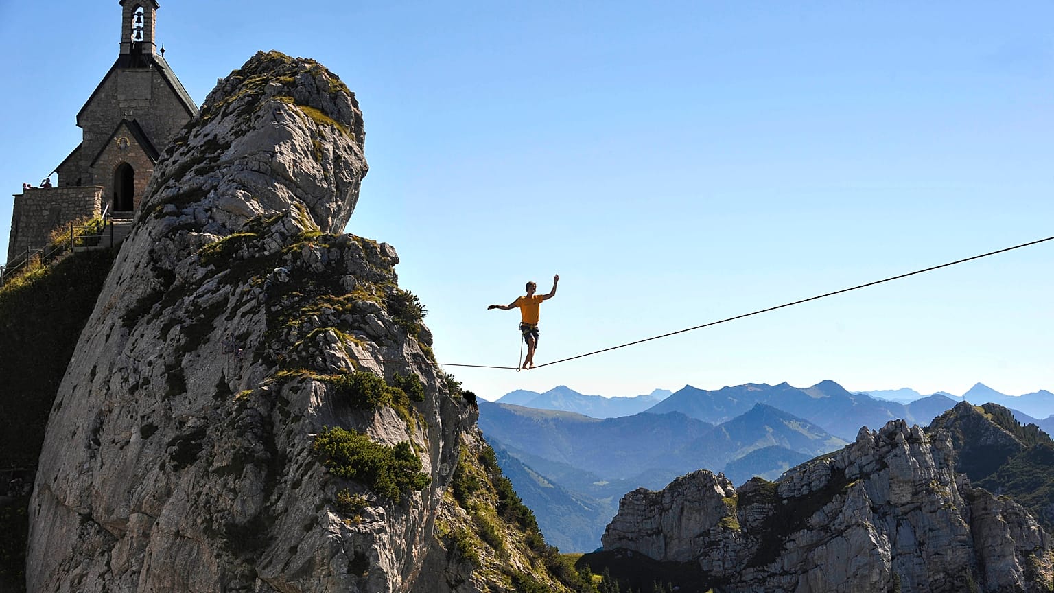 A Slackliner walks on a highline at Wendelstein mountain near Bayrisch Zell ,in the Bavarian Alps, southern Germany