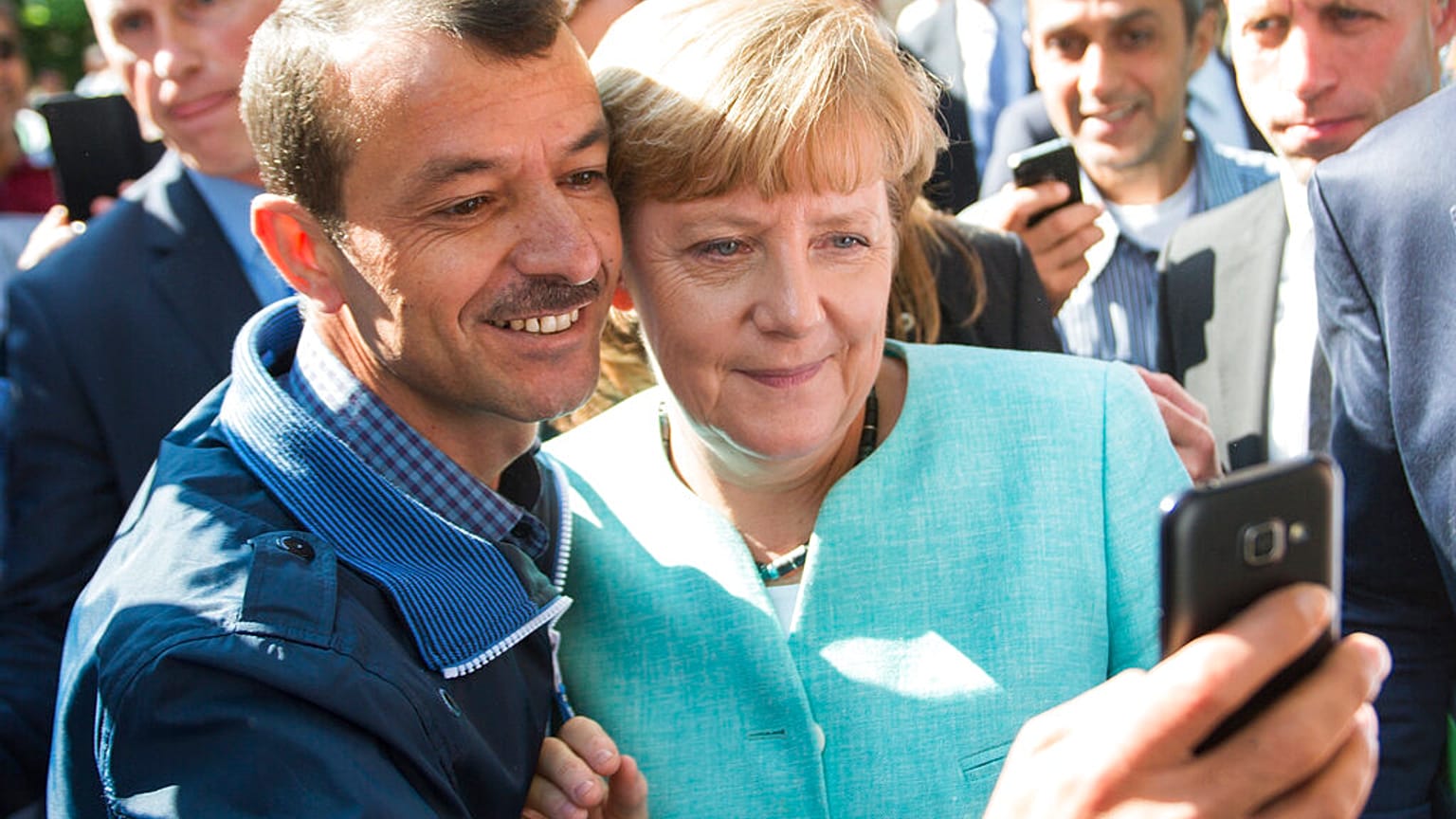 2015'te Suriyeli mültecilere Almanya'nın kapılarını açan Başbakan Angela Merkel'le fotoğraf çektiren bir sığınmacı