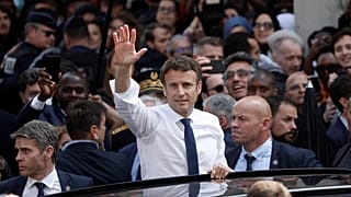 الرئيس الفرنسي إيمانويل ماكرون يلوح من سيارته بعد زيارته لإحدى ضواحي باريس. 2022/04/27