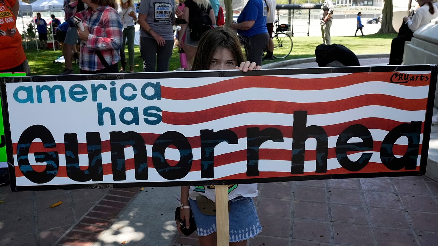 Участница протеста за ужесточение контроля за оружием с плакатом "У Америки Gun-орея"