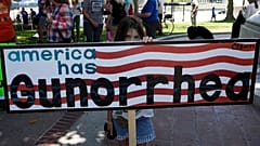 Участница протеста за ужесточение контроля за оружием с плакатом "У Америки Gun-орея"