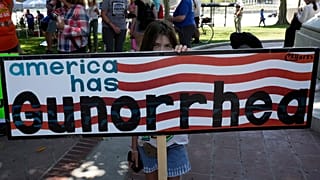 Участница протеста за ужесточение контроля за оружием с плакатом "У Америки Gun-орея"