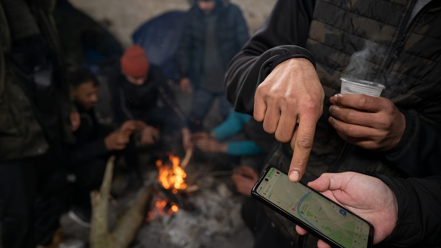 مهاجرون يتحققون من خارطة رقمية للمنطقة الحدودية المجرية الصربية، أثناء وجودهم داخل حظيرة مهجورة بالقرب من الحدود بين البلدين، 11 يناير 2022