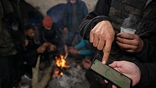 مهاجرون يتحققون من خارطة رقمية للمنطقة الحدودية المجرية الصربية، أثناء وجودهم داخل حظيرة مهجورة بالقرب من الحدود بين البلدين، 11 يناير 2022
