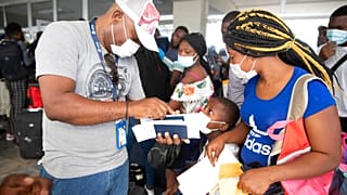 Haitianos esperan para subirse a un vuelo chárter en dirección a Chile en el aeropuerto de Puerto Príncipe, Haití