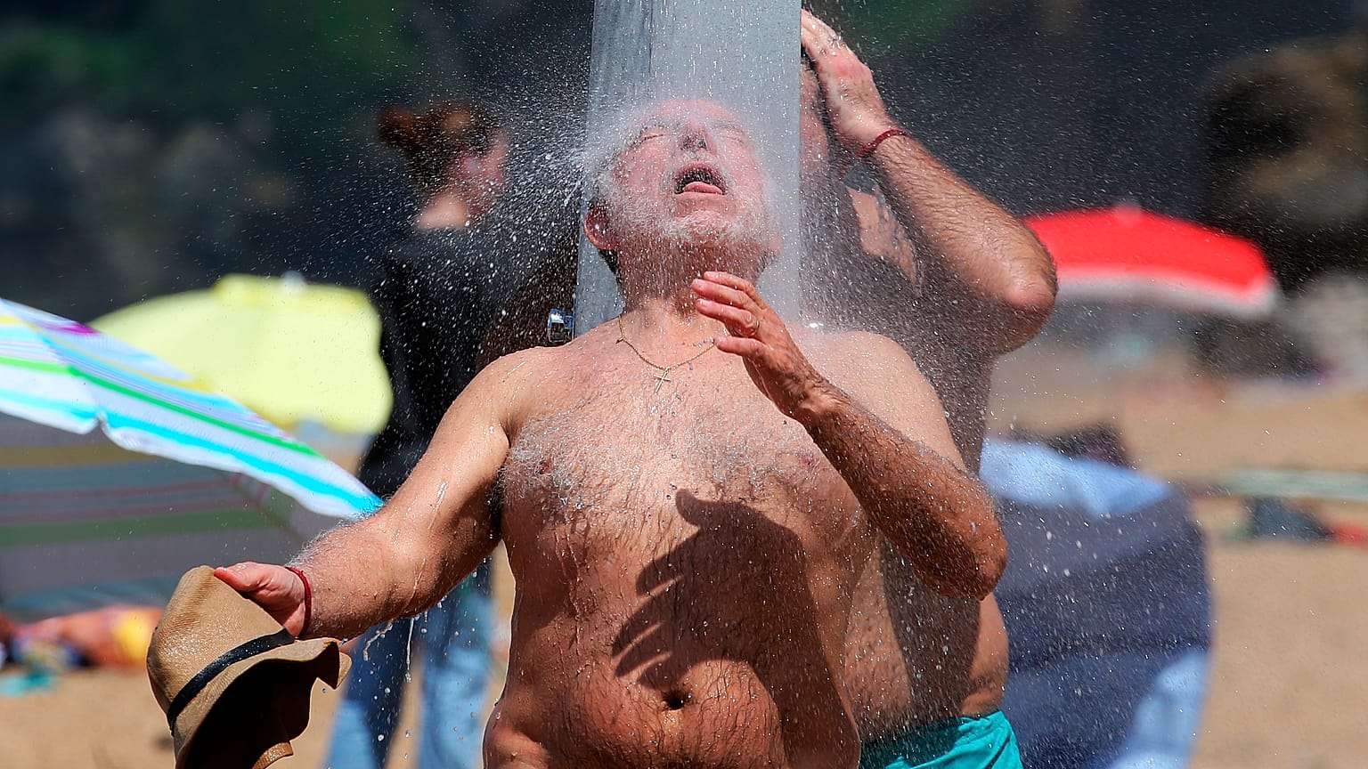 People cool down under a shower at Biarritz beach, southwestern France, Wednesday, May 18, 2022. 