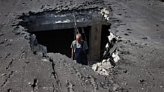 A man examines the roof of a hospital damaged during shelling in Donetsk, eastern Ukraine, Tuesday, June 14, 2022.