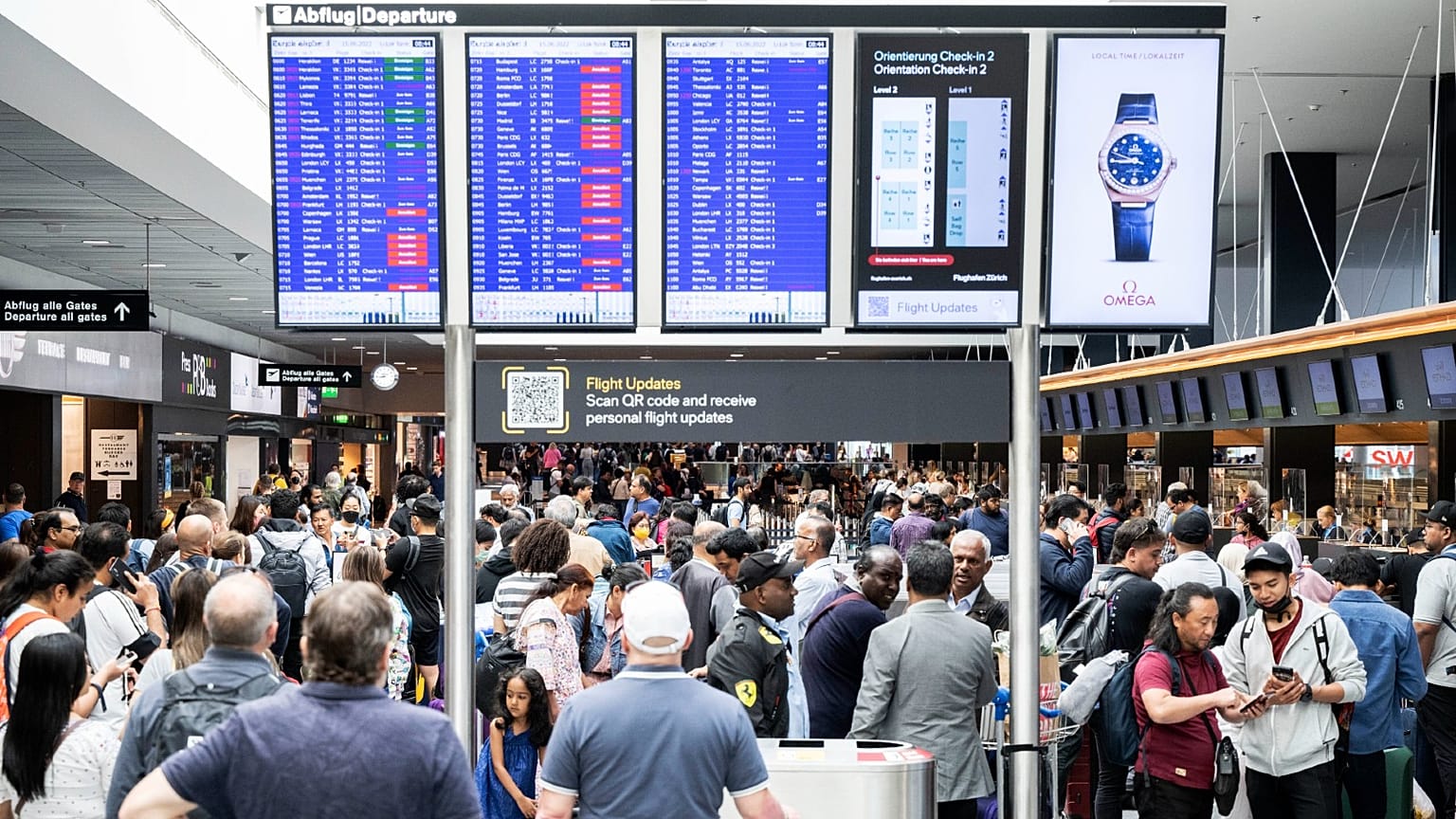 assengers wait in front of a display board at Zurich airport, in Zurich, Wednesday, June 15, 2022