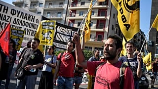A man holds a flag as hundreds of protesters gather outside the courthouse in Athens.