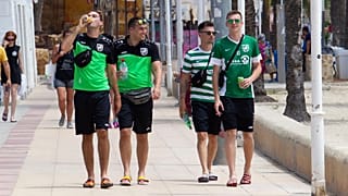 Tourists walk on the promenade at Magaluf Beach in Calvia, on the Balearic Island of Majorca.