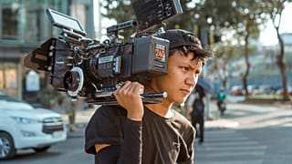 A man carries a film camera