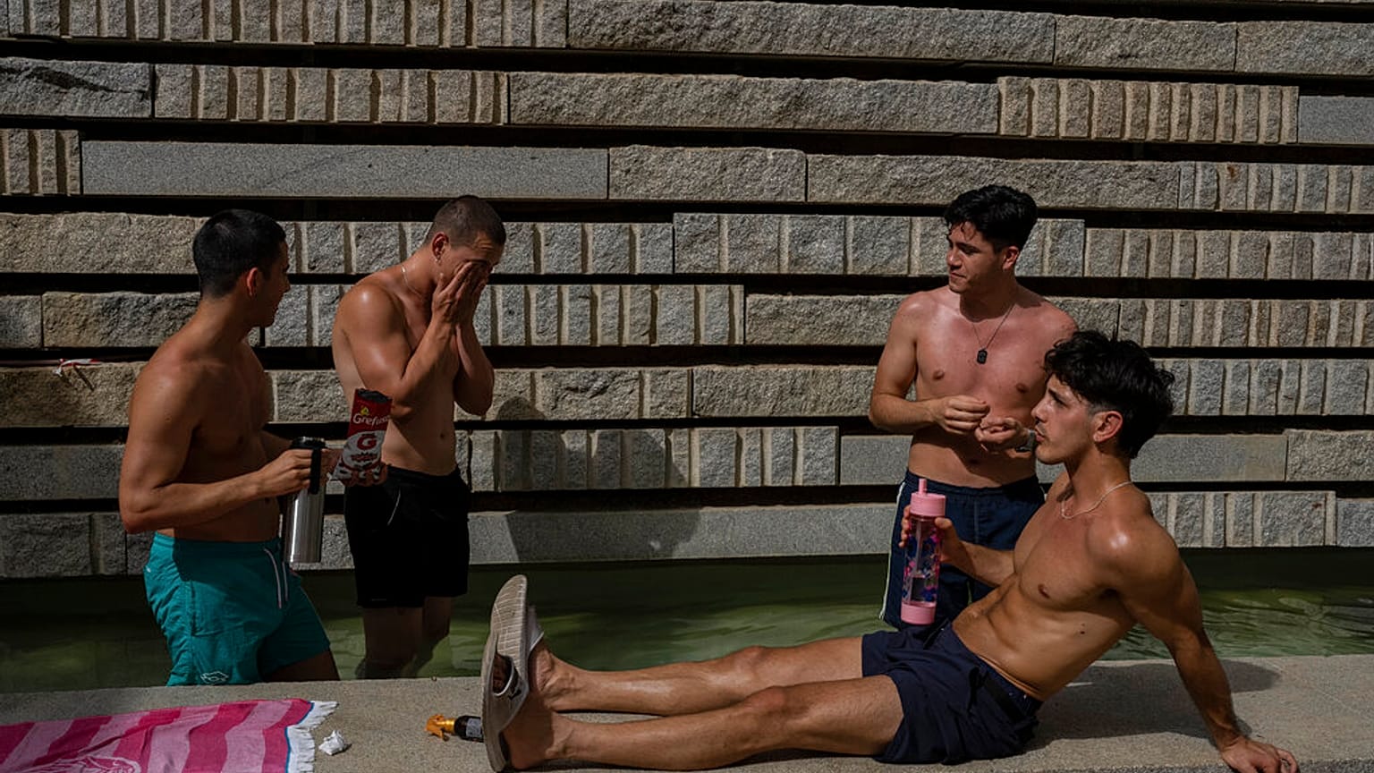 Varias personas se refrescan en un parque de Madrid