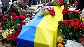 A solider kneels at activist and soldier Roman Ratushnyi's coffin during the memorial service in Kyiv, Ukraine, June 18, 2022