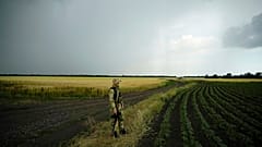 A Russian soldier guards an area next to a field of wheat in the Zaporizhzhia region in an area under Russian military control, 14 June 2022