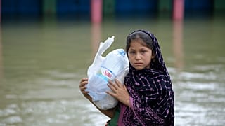 طفلة بنغالية تحمل مواد إغاثة في منطقة كومبانيغونج في سيلهيت التي تضررت بفعل الفيضانات،  20 يونيو 2022.