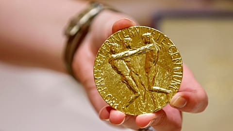 A worker holds Dmitry Muratov's 23-karat gold medal of the 2021 Nobel Peace Prize before being auctioned at the Times Center, June 20, 2022, in New York