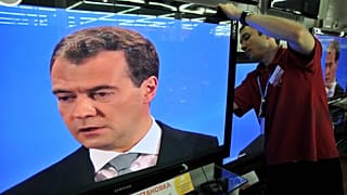 A Moscow shop assistant works on May 18, 2011, amidst TV screens during the broadcast of Russian President Dmitry Medvedev's televised news conference.