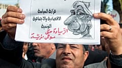 عامل تونسي يرفع ملصقًا كتب عليه: "كريستين لاغارد امرأة تدعم السياسة والاقتصادية والاجتماعية التونسية، الزيادة حق وليست منة". 2018/11/22
