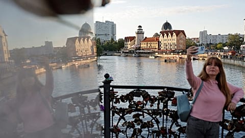 A woman takes a selfie on an embankment of the Pregolya River in Kaliningrad