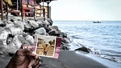Joseph Gustave, propriétaire du restaurant Mélodie, compare la même plage à 50 ans d’écart, sur la plage du Prêcheur, en Martinique, le 17 juin 2022. 