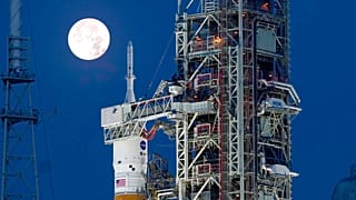 The Strawberry Supermoon sets in front of the NASA Artemis rocket with the Orion spacecraft aboard on pad 39B at the Kennedy Space Center