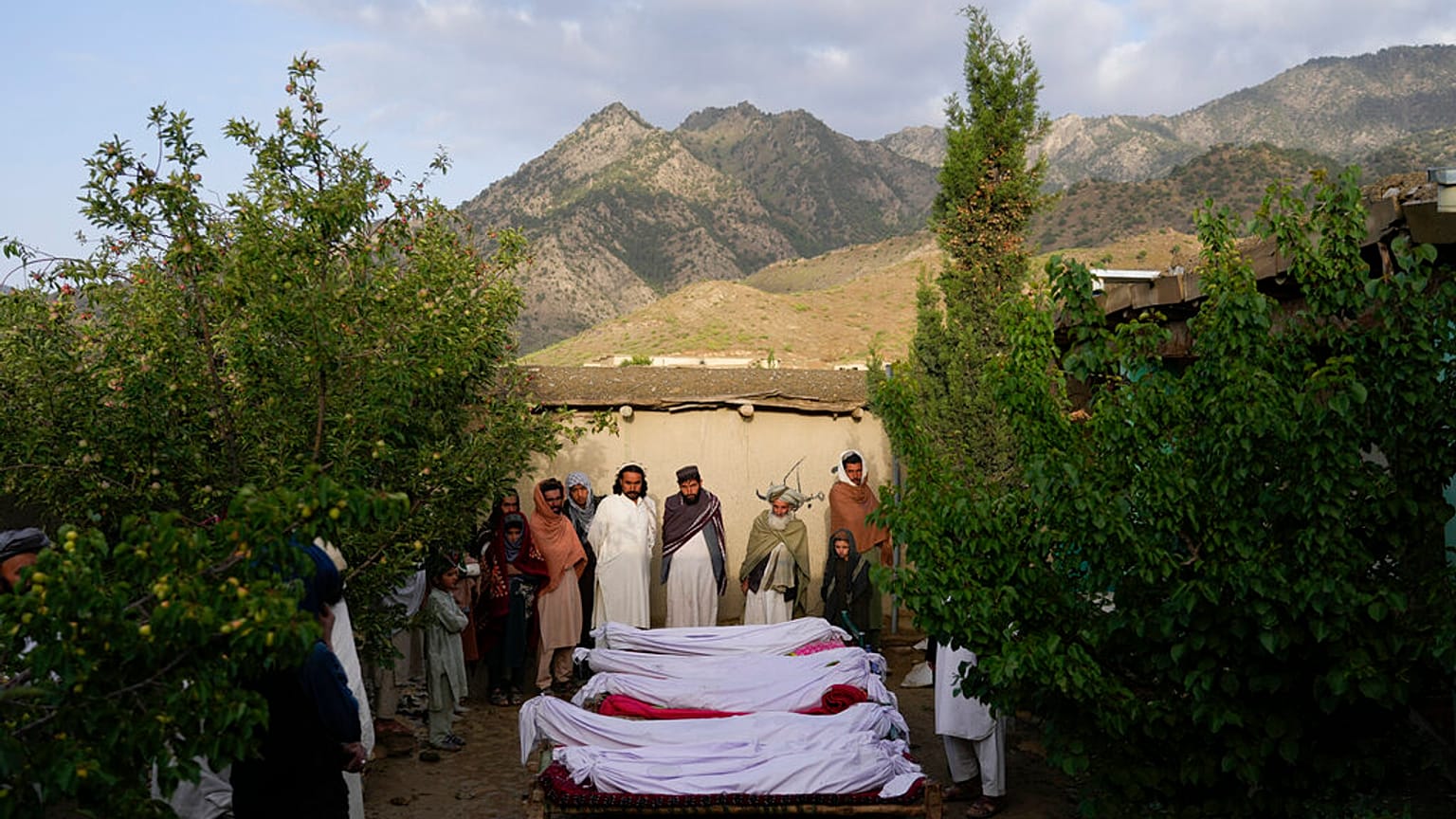 Men stand around the bodies of people killed in an earthquake in Gayan village, in Paktika province, Afghanistan
