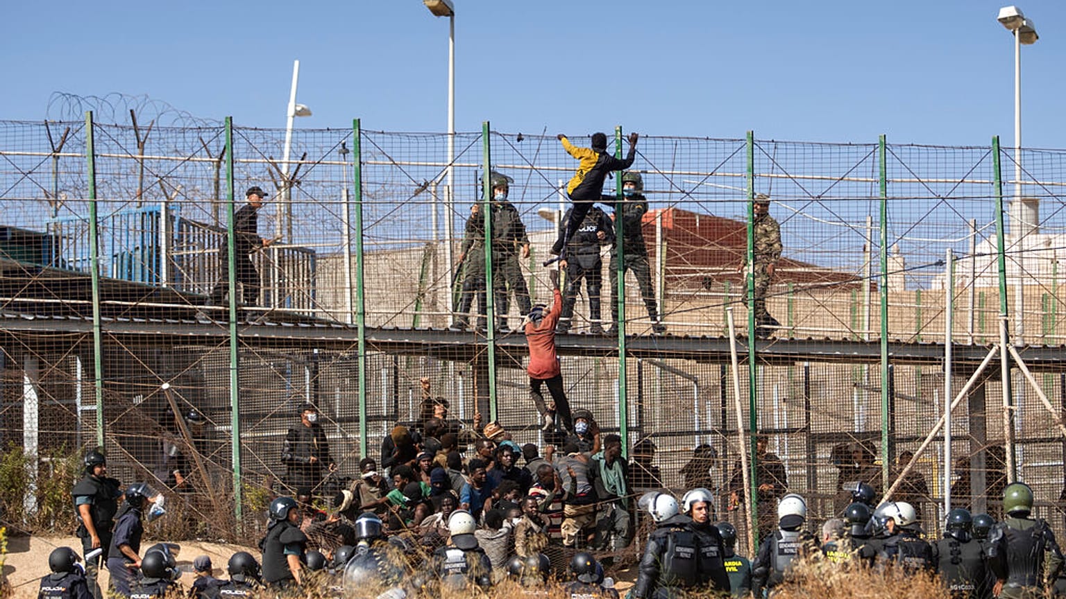 Des hommes escaladent les clôtures séparant l'enclave espagnole de Melilla du Maroc à Melilla, en Espagne, vendredi 24 juin 2022.