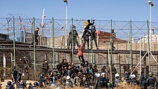 Des hommes escaladent les clôtures séparant l'enclave espagnole de Melilla du Maroc à Melilla, en Espagne, vendredi 24 juin 2022.