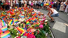 Des personnes déposent des fleurs sur les lieux d'une fusillade près d'un club gay dans le centre d'Oslo, en Norvège, samedi 25 juin 2022. 