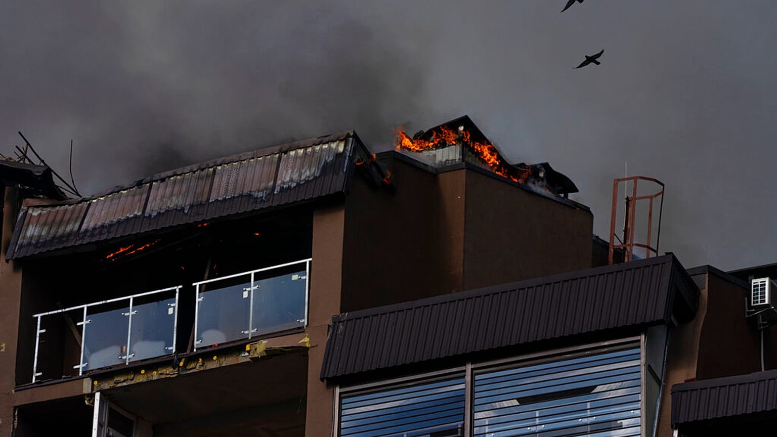 Des oiseaux survolent un immeuble résidentiel après des explosions, à Kyiv, en Ukraine, dimanche 26 juin 2022. 