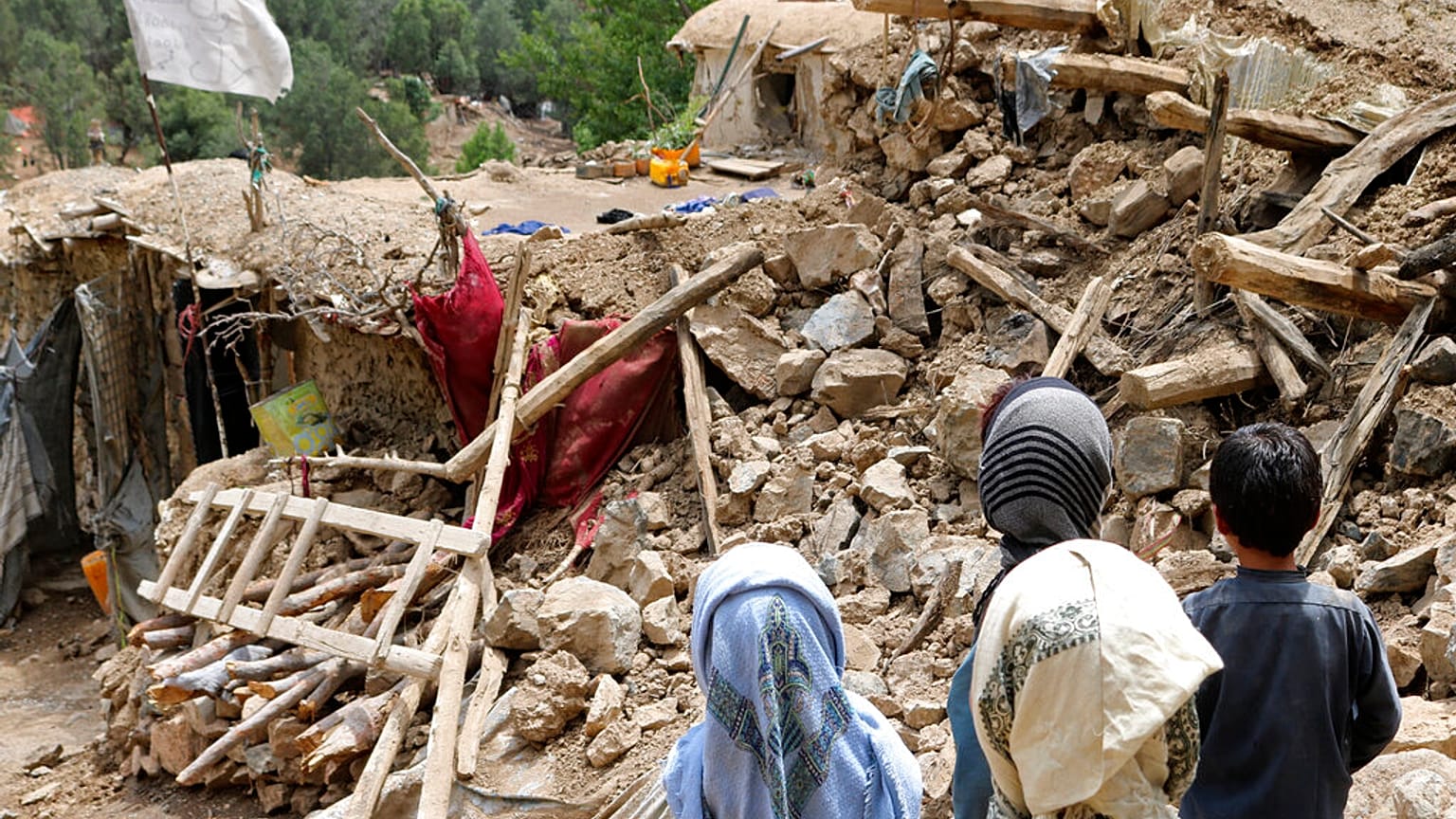 Afghan children stand near a house that was destroyed in an earthquake