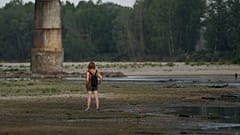 Une femme se tient sur le lit du Pô à côté du pont de la Becca à Linarolo, près de Pavie, en Italie, lundi 27 juin 2022.