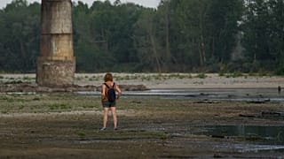 Une femme se tient sur le lit du Pô à côté du pont de la Becca à Linarolo, près de Pavie, en Italie, lundi 27 juin 2022.