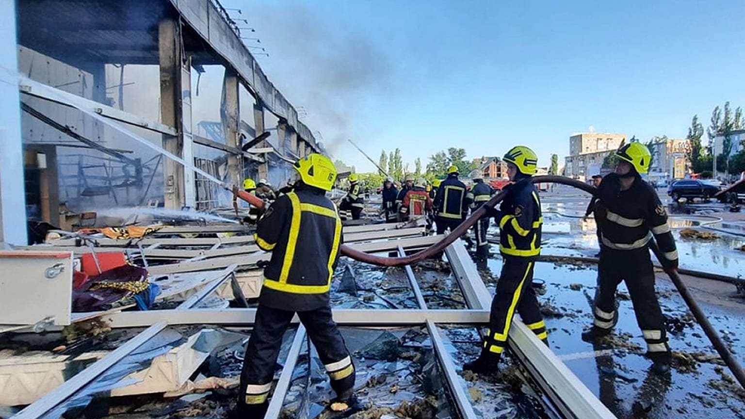 Firefighters work to extinguish a fire at a shopping center burned after a rocket attack in Kremenchuk on 27 June 2922