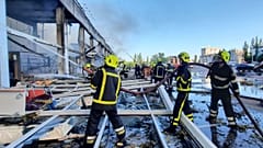 Firefighters work to extinguish a fire at a shopping center burned after a rocket attack in Kremenchuk on 27 June 2922